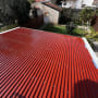 גג מתכת אדום עם ברגים בגינה