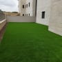דשא ירוק מלאכותי בחצר ליד בניין