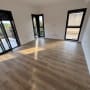 חדר ריק עם רצפת עץ נקייה וחלונות גדולים