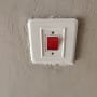 מתג חשמלי עם כפתור אדום על קיר