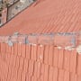 גג רעפים אדום עם צינור מתכת וחיבורים מתקלפים