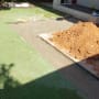עבודות שיפוץ בחצר עם ערימת אדמה ודשא סינתטי