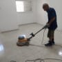אדם מנקה רצפה עם מכונת פוליש בחדר ריק