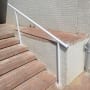 מעקה לבן על מדרגות לבנים ליד קיר מרוצף