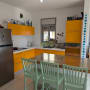מטבח עם ארונות צהובים, מקרר נירוסטה וכיסאות ירוקים