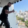 אדם מתקין רשת למניעת כניסת יונים במרפסת