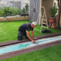 אדם מתקין דשא סינתטי בגינה עם כלים
