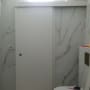 דלת הזזה לבנה בחדר אמבטיה עם קירות שיש