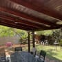 פרגולה מעץ בגינה עם שולחן וכיסאות מתכת
