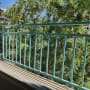 מעקה מתכת ירוק במרפסת עם עצים ברקע