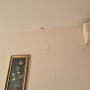 כתם רטיבות על קיר ליד תמונה ומזגן