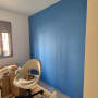 קיר צבוע בכחול בחדר עם כיסא ומיטה