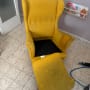 כיסא צהוב עם כתמים וכלי ניקוי על הרצפה