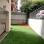 דשא סינתטי בחצר מגודרת עם צמחייה ירוקה