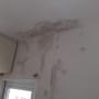 קיר ותקרה עם סימני רטיבות ותיקוני צבע