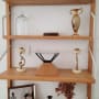 מדף עץ עם פסלים, אגרטלים ונרות דקורטיביים