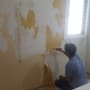 אדם מקלף צבע מקיר בעזרת שפכטל