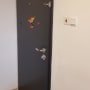 דלת שחורה עם ידית מתכת ודלי צבע אדום