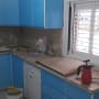 מטבח בשיפוץ עם ארונות כחולים, כלים וחומרים על השיש