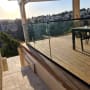 מעקה זכוכית על מרפסת עץ עם נוף עירוני