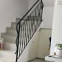 מעקה מתכת שחור עם עיטורים על מדרגות לבנות