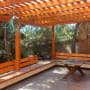 פרגולה מעץ עם ספסלים ושולחן בגינה
