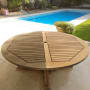 שולחן עץ עגול ליד בריכת שחייה בגינה