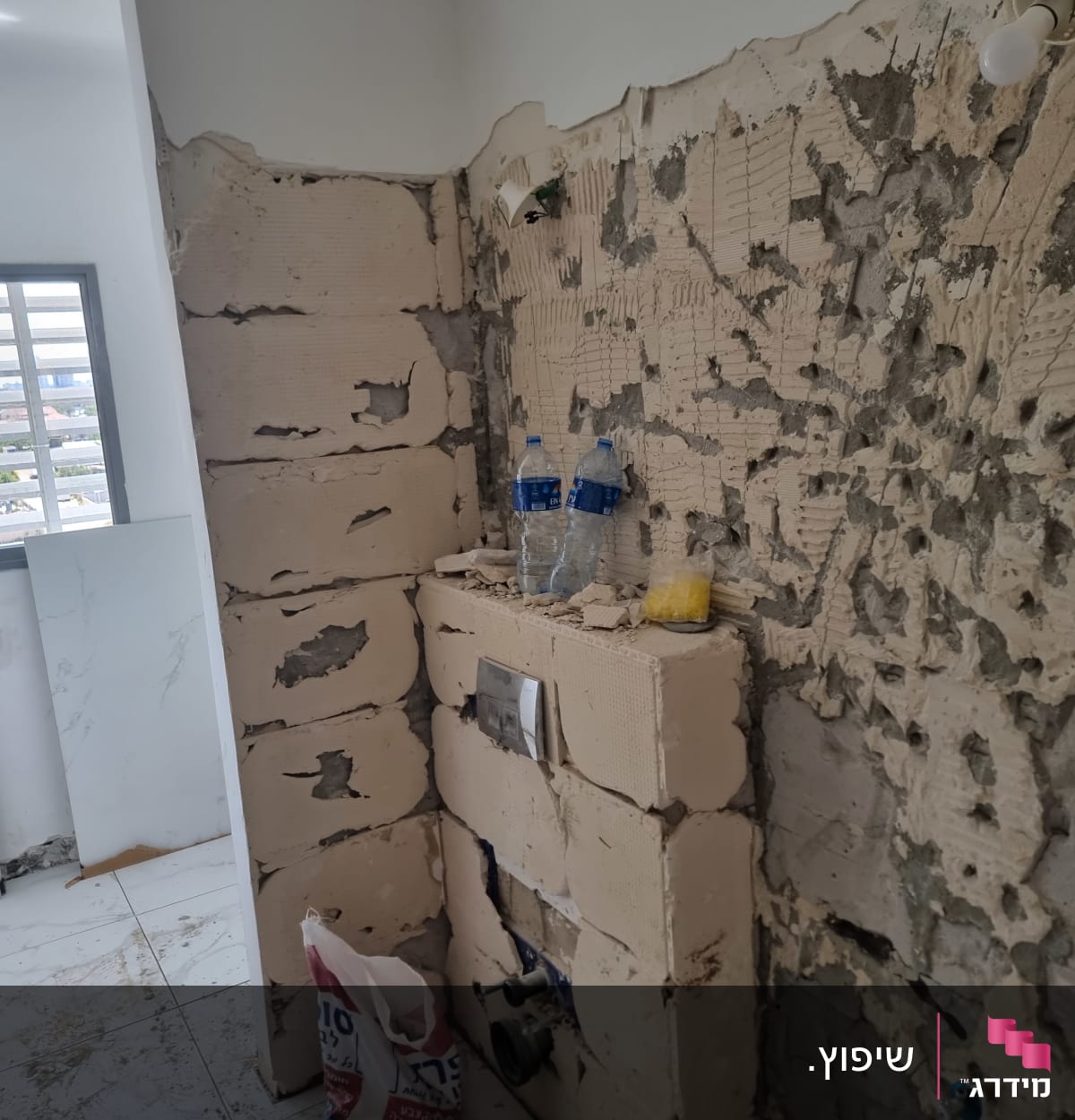 קיר מתקלף עם סימני שיפוץ, אריחים מונחים על הרצפה