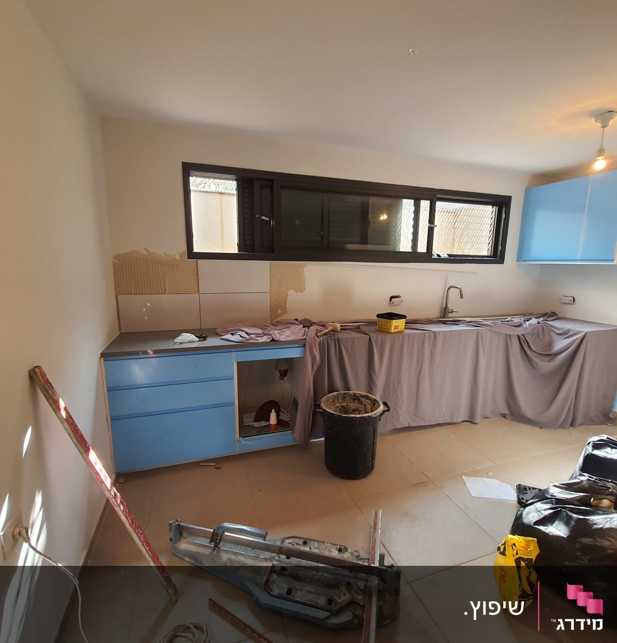 מטבח בשיפוץ עם כלים וחומרים על הרצפה