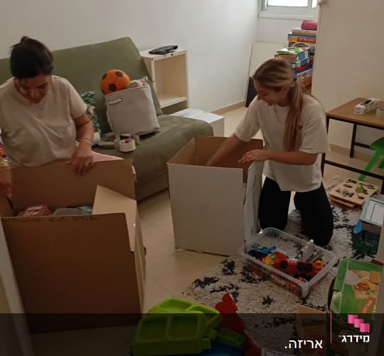שתי נשים אורזות קופסאות בחדר עם צעצועים