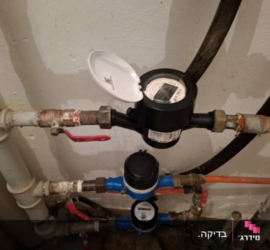 מד מים וצינורות עם ברזים אדומים
