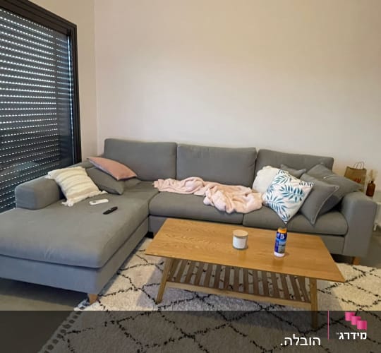 ספה אפורה עם כריות ושלט על שולחן עץ