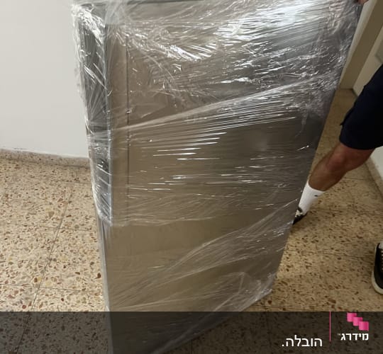 אדם מחזיק חפץ עטוף בניילון על רצפה