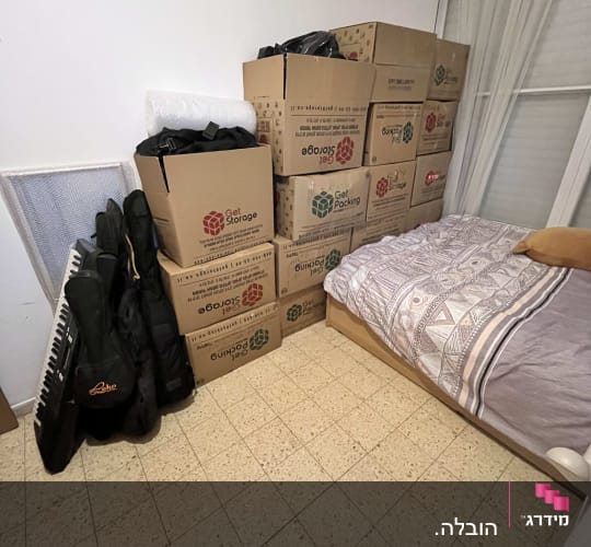 קופסאות קרטון לאריזה מונחות בחדר ליד מיטה