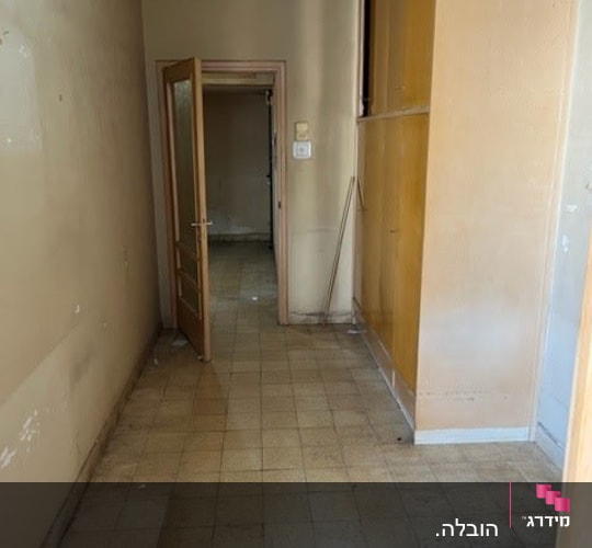 מסדרון ריק עם דלת פתוחה ומקל מטאטא