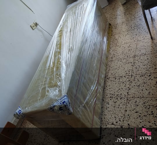 רהיט עטוף בניילון מוכן להובלה על רצפת טרצו