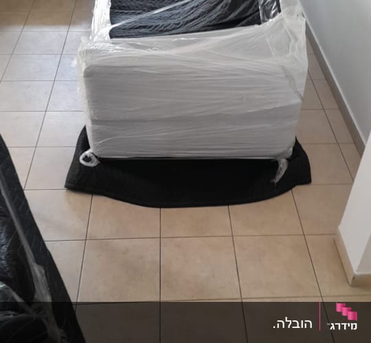 רהיט עטוף בניילון מוכן להובלה על רצפת אריחים