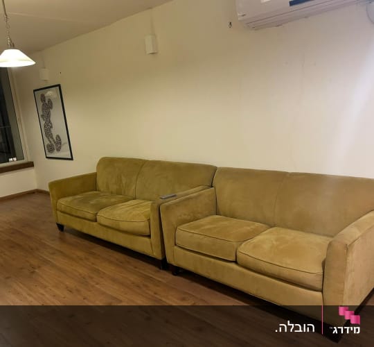 ספה חומה על רצפת עץ בחדר ריק