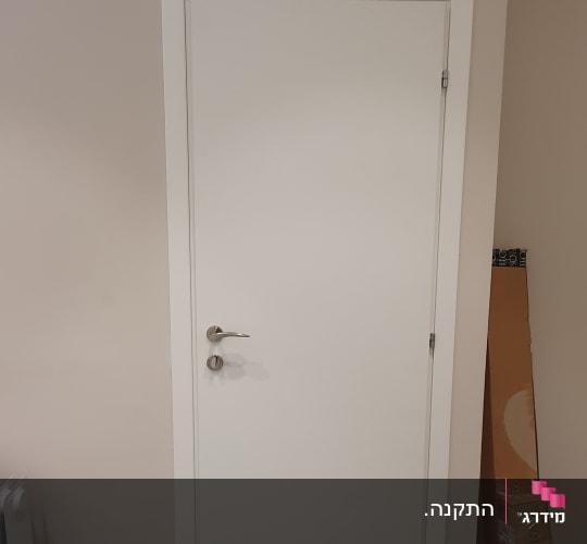 דלת לבנה עם ידית מתכת על קיר בהיר