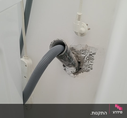 צינור מחובר לקיר ליד מכונת כביסה