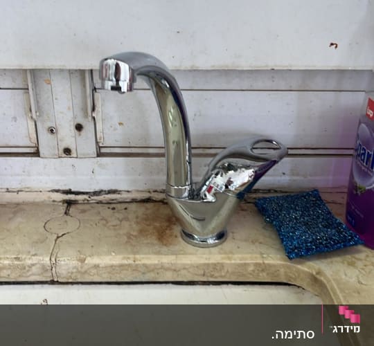 ברז כרום מותקן על כיור מטבח עם ספוג ניקוי