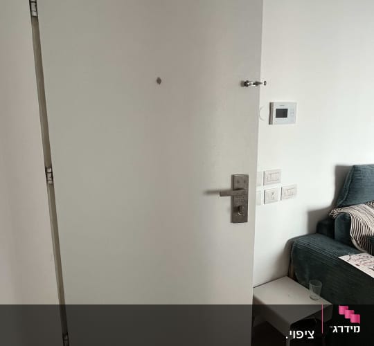 דלת כניסה לבית בעלת ציפוי לבן חלק עם עינית ומנעול ביטחון