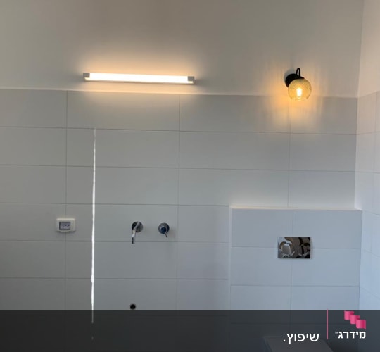 קיר אריחים לבנים עם גופי תאורה וברזים