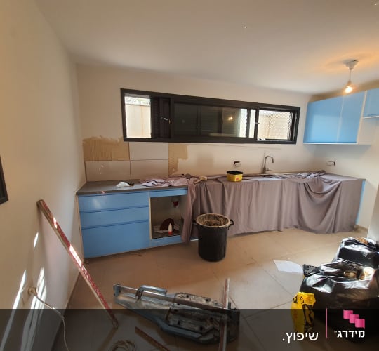 מטבח בשיפוץ עם כלים וחומרים על הרצפה