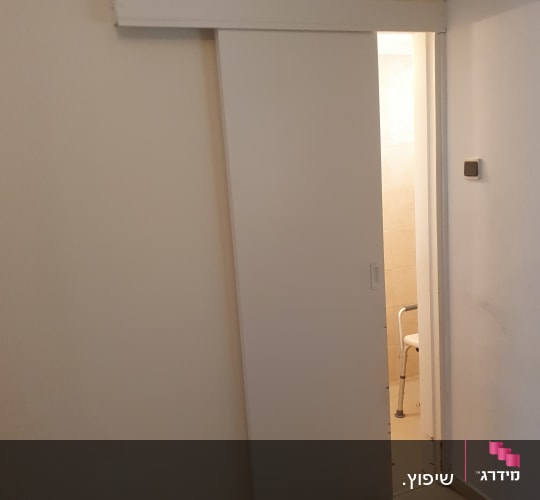 דלת הזזה לבנה מותקנת על מסילה בקיר