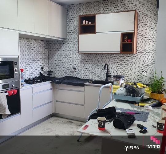 מטבח בשיפוץ עם כלים וחומרים על השיש