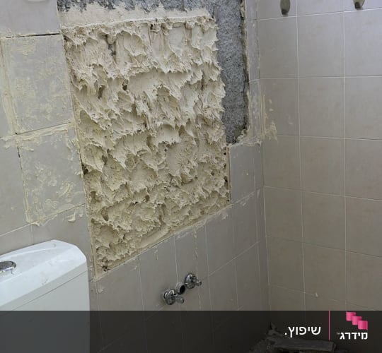 חדר אמבטיה עם קיר מתקלף ותיקונים