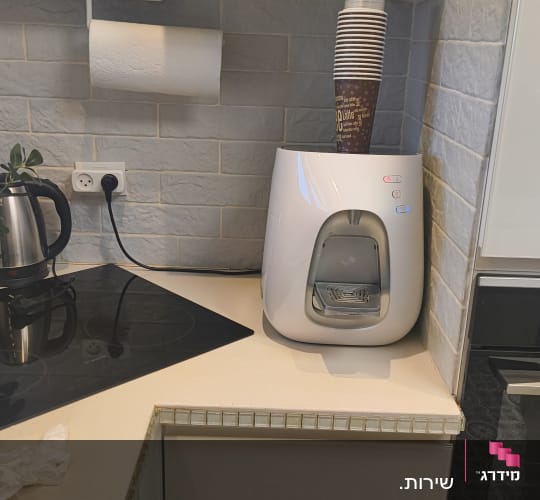 מטבח עם מכונת קפה וכוסות חד פעמיות