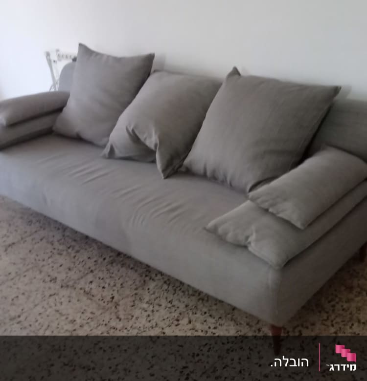 ספה אפורה עם כריות על רצפת טרצו