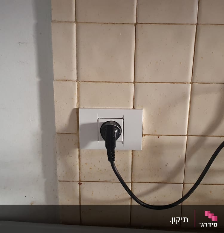 שקע חשמלי עם תקע מחובר על קיר מרוצף